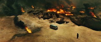 Movie still from “Black Adam” (2022), directed by Jaume Collet-Serra – A van driving down a dirt road in front of a burning field; Extreme Wide shot, High angle