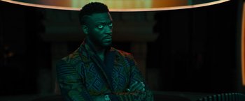 Movie still from “Black Adam” (2022), directed by Jaume Collet-Serra – A man in a colorful jacket with his arms crossed; Close Up shot, Over the shoulder angle