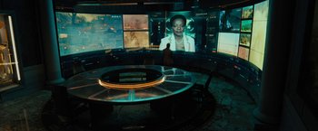 Movie still from “Black Adam” (2022), directed by Jaume Collet-Serra – A person is standing in front of a large screen; Wide shot, High angle