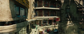 Movie still from “Black Adam” (2022), directed by Jaume Collet-Serra – A street view of a building with people walking on the sidewalk; Extreme Wide shot, High angle
