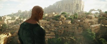 Movie still from “Black Adam” (2022), directed by Jaume Collet-Serra – A man looking out over a city from a hill; Extreme Wide shot, Over the shoulder angle
