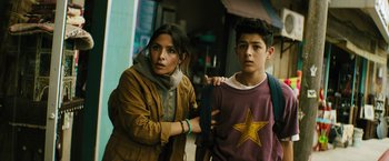 Movie still from “Black Adam” (2022), directed by Jaume Collet-Serra – A woman standing next to a young boy; Medium shot, Over the shoulder angle