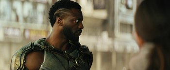 Movie still from “Black Adam” (2022), directed by Jaume Collet-Serra – A person with a beard looking to the side; Close Up shot, Over the shoulder angle