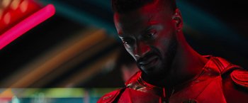 Movie still from “Black Adam” (2022), directed by Jaume Collet-Serra – A person with a red light in the background; Close Up shot, Over the shoulder angle