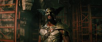 Movie still from “Black Adam” (2022), directed by Jaume Collet-Serra – A man in a costume with a bird on his head; Medium shot, Low angle