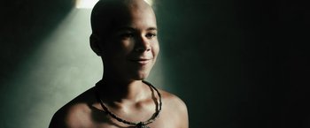 Movie still from “Black Adam” (2022), directed by Jaume Collet-Serra – A man with a shaved head wearing a necklace; Close Up shot, High angle