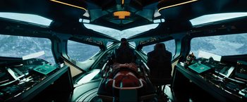 Movie still from “Black Adam” (2022), directed by Jaume Collet-Serra – A view from inside an airplane of a person on a plane; Extreme Wide shot, Overhead angle