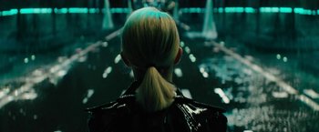 Movie still from “Black Adam” (2022), directed by Jaume Collet-Serra – A woman with blonde hair is wearing a black jacket; Close Up shot, Over the shoulder angle