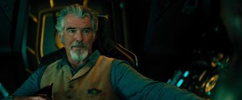 Movie still from “Black Adam” (2022), directed by Jaume Collet-Serra – An older man sitting in a chair taking a selfie; Close Up shot, Over the shoulder angle