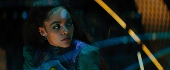 Movie still from “Black Adam” (2022), directed by Jaume Collet-Serra – A woman in a blue jacket is looking at the camera; Close Up shot, Over the shoulder angle