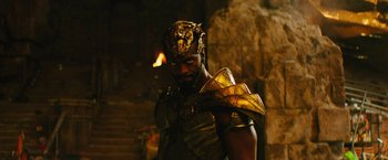 Movie still from “Black Adam” (2022), directed by Jaume Collet-Serra – A man wearing a gold armor and helmet; Medium shot, Over the shoulder angle