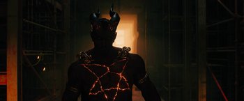 Movie still from “Black Adam” (2022), directed by Jaume Collet-Serra – A man in a costume is standing in a dark room; Medium shot, High angle