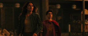 Movie still from “Black Adam” (2022), directed by Jaume Collet-Serra – A woman and a young boy standing next to each other; Medium shot, Over the shoulder angle