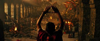 Movie still from “Black Adam” (2022), directed by Jaume Collet-Serra – A man holding his hands up in the air in front of a crowd of people; Extreme Wide shot, Overhead angle