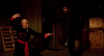 Two men are practicing martial arts in a dark room