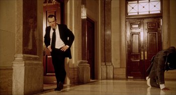 Movie still from “Black Dynamite” (2009), directed by Scott Sanders – A man in a suit and tie standing in front of a door way; Wide shot, Low angle