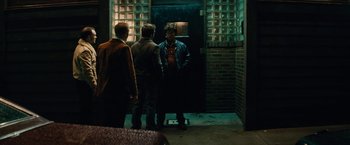 Movie still from “Black Mass” (2015), directed by Scott Cooper – A group of men standing in front of a building; Medium shot, Over the shoulder angle