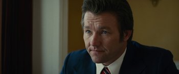 Movie still from “Black Mass” (2015), directed by Scott Cooper – A person wearing a suit and tie; Close Up shot, Over the shoulder angle