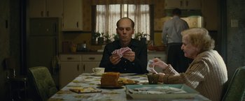 Movie still from “Black Mass” (2015), directed by Scott Cooper – A man sitting at a table playing cards with other people; Medium shot, High angle