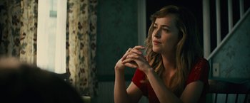 A woman sitting at a table with her hands up to her face