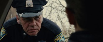 Movie still from “Black Mass” (2015), directed by Scott Cooper – A police officer is looking down at the ground; Close Up shot, Over the shoulder angle