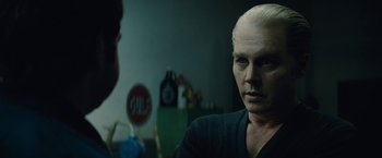 Movie still from “Black Mass” (2015), directed by Scott Cooper – A man with a shaved head is talking to another man in a dark room; Close Up shot, Over the shoulder angle