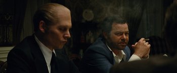 Movie still from “Black Mass” (2015), directed by Scott Cooper – Two men in suits sitting next to each other in a room; Close Up shot, Over the shoulder angle