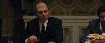 Movie still from “Black Mass” (2015), directed by Scott Cooper – A man sitting at a table with a cup of coffee; Close Up shot, Over the shoulder angle