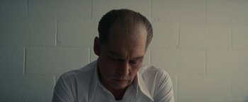 Movie still from “Black Mass” (2015), directed by Scott Cooper – A man in a white dress shirt is looking down; Close Up shot, Low angle