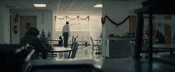 Movie still from “Black Mass” (2015), directed by Scott Cooper – A man standing in a room with a bunch of chairs; Wide shot, Over the shoulder angle