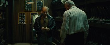 Movie still from “Black Mass” (2015), directed by Scott Cooper – Two men standing next to each other in front of a fireplace; Medium shot, Over the shoulder angle