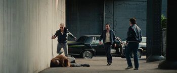 Movie still from “Black Mass” (2015), directed by Scott Cooper – A group of men standing around a man lying on the ground; Wide shot, High angle
