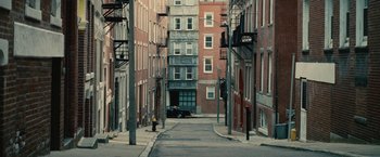 Movie still from “Black Mass” (2015), directed by Scott Cooper – An empty street with a fire hydrant on one side and buildings on the other side; Extreme Wide shot, High angle