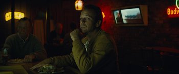 Movie still from “Black Mass” (2015), directed by Scott Cooper – A man sitting at a table in front of a television; Medium shot, Low angle