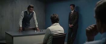 Movie still from “Black Mass” (2015), directed by Scott Cooper – Two men in suits and ties in a interrogation room; Medium shot, Over the shoulder angle