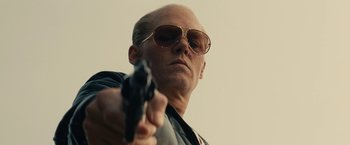 Movie still from “Black Mass” (2015), directed by Scott Cooper – A man in sunglasses holding a gun pointed at the sky; Close Up shot, Low angle
