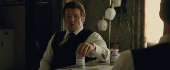 Movie still from “Black Mass” (2015), directed by Scott Cooper – A man sitting at a table with two cans of beer; Close Up shot, Over the shoulder angle