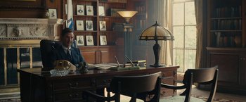 Movie still from “Black Mass” (2015), directed by Scott Cooper – A man sitting at a desk in front of a desk lamp; Wide shot, Low angle