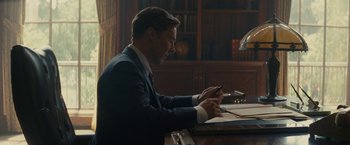 Movie still from “Black Mass” (2015), directed by Scott Cooper – A man sitting at a table writing on a piece of paper; Medium shot, High angle