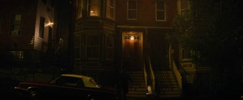 Movie still from “Black Mass” (2015), directed by Scott Cooper – A person standing in front of a building at night; Extreme Wide shot, High angle