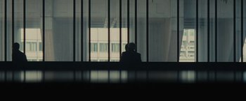Movie still from “Black Mass” (2015), directed by Scott Cooper – A person sitting in front of a large window; Wide shot, Over the shoulder angle
