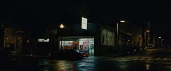 Movie still from “Black Mass” (2015), directed by Scott Cooper – A car parked in front of a store at night; Extreme Wide shot, High angle
