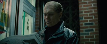 Movie still from “Black Mass” (2015), directed by Scott Cooper – Johnny depp in black leather jacket reading a newspaper; Close Up shot, Low angle