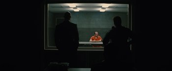 Movie still from “Black Mass” (2015), directed by Scott Cooper – A man in an interrogation room with two other men looking at him; Wide shot, Over the shoulder angle