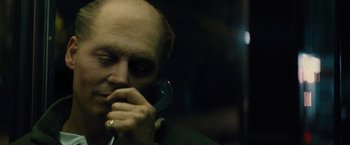 Movie still from “Black Mass” (2015), directed by Scott Cooper – A man holding a phone up to his ear; Close Up shot, Low angle