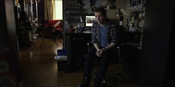 Movie still from “Blair Witch” (2016), directed by Adam Wingard – A man sitting on a chair in a room; Medium shot, High angle