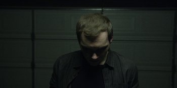 Movie still from “Blair Witch” (2016), directed by Adam Wingard – A man in a black shirt is looking down at his face; Close Up shot, Low angle
