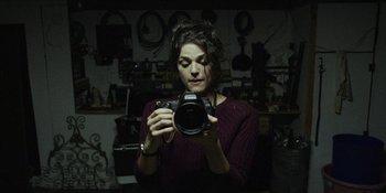 Movie still from “Blair Witch” (2016), directed by Adam Wingard – A woman is holding a camera in a room; Close Up shot, Low angle