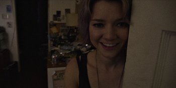 Movie still from “Blair Witch” (2016), directed by Adam Wingard – A young woman smiling for the camera in a kitchen; Close Up shot, Overhead angle