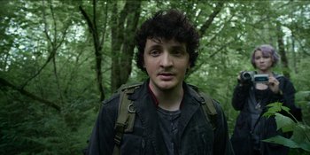 Movie still from “Blair Witch” (2016), directed by Adam Wingard – A man with a backpack standing in the woods; Close Up shot, Low angle